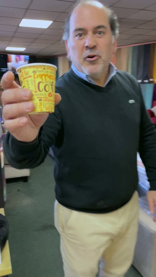 El dueño saluda con un café en la mano