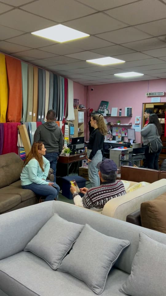 El salón lleno de clientes con el muro de telas de colores